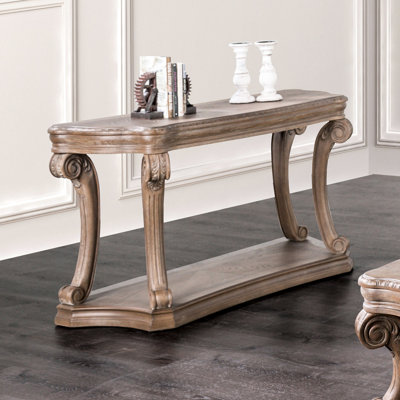 Table traditionnelle en bois massif de style transitionnel avec pattes en volute, tablette ouverte et moulures dentelées, chêne vieilli, 137 cm de long x 51 cm de profondeur. Détails soignés. Couleur du chêne. Dimensions : 137 cm (l) x 51 cm (p) x 76 cm (h).