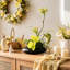Composition florale d'orchidées jaunes artificielles, centre de table de fleurs artificielles avec vase en forme de galet noir, feuillage et mousse mélangés