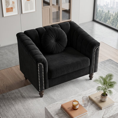 Fauteuil capitonné noir, accoudoirs arrondis et garniture cloutée