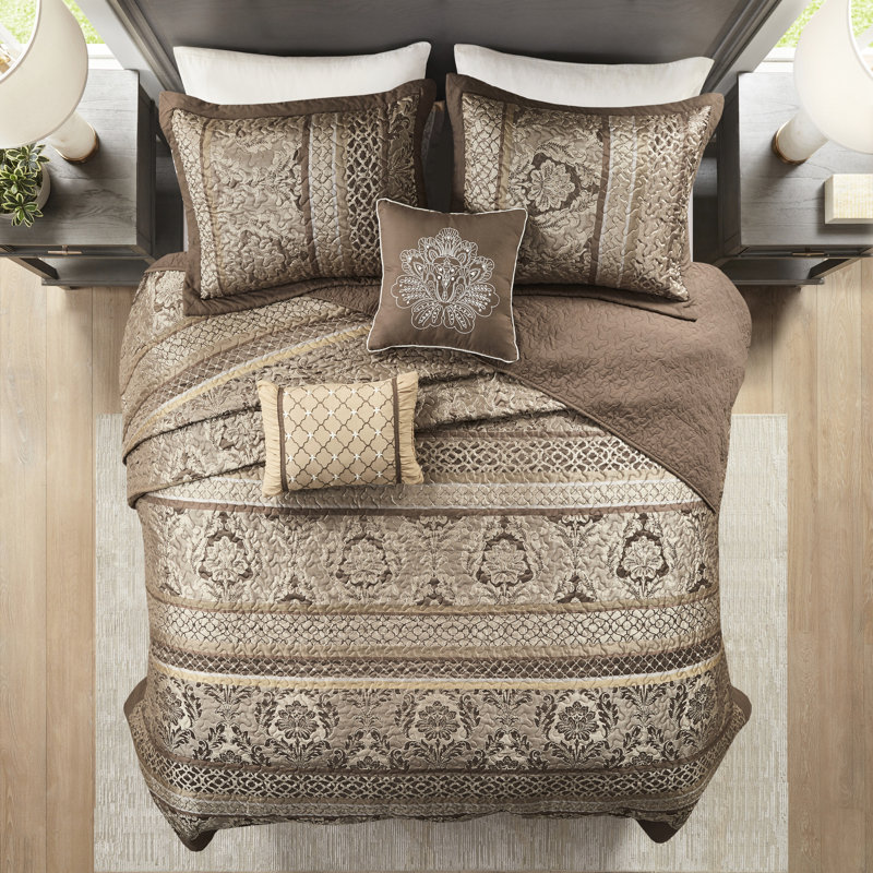 5 couvre-lits - grand. Brun et or. Comprend un couvre-lit, 2 taies décoratives et des coussins décoratifs. Fabriqué avec pour une durabilité de luxe. Affiche des feuilles, des rayures, des motifs. Surpiqûres ornées. Les détails dorés ajoutent de l'élégance.