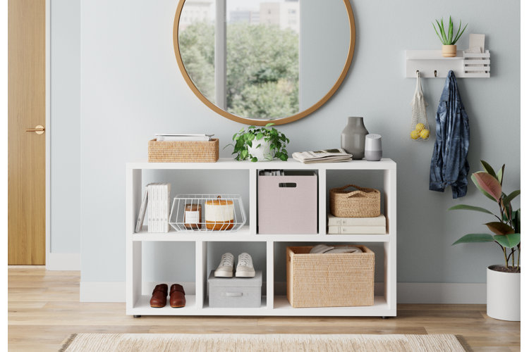 entryway with a white cubby bookcase filled with woven and metal baskets as well as box storage and round wall mirror next to a white mail organizer
