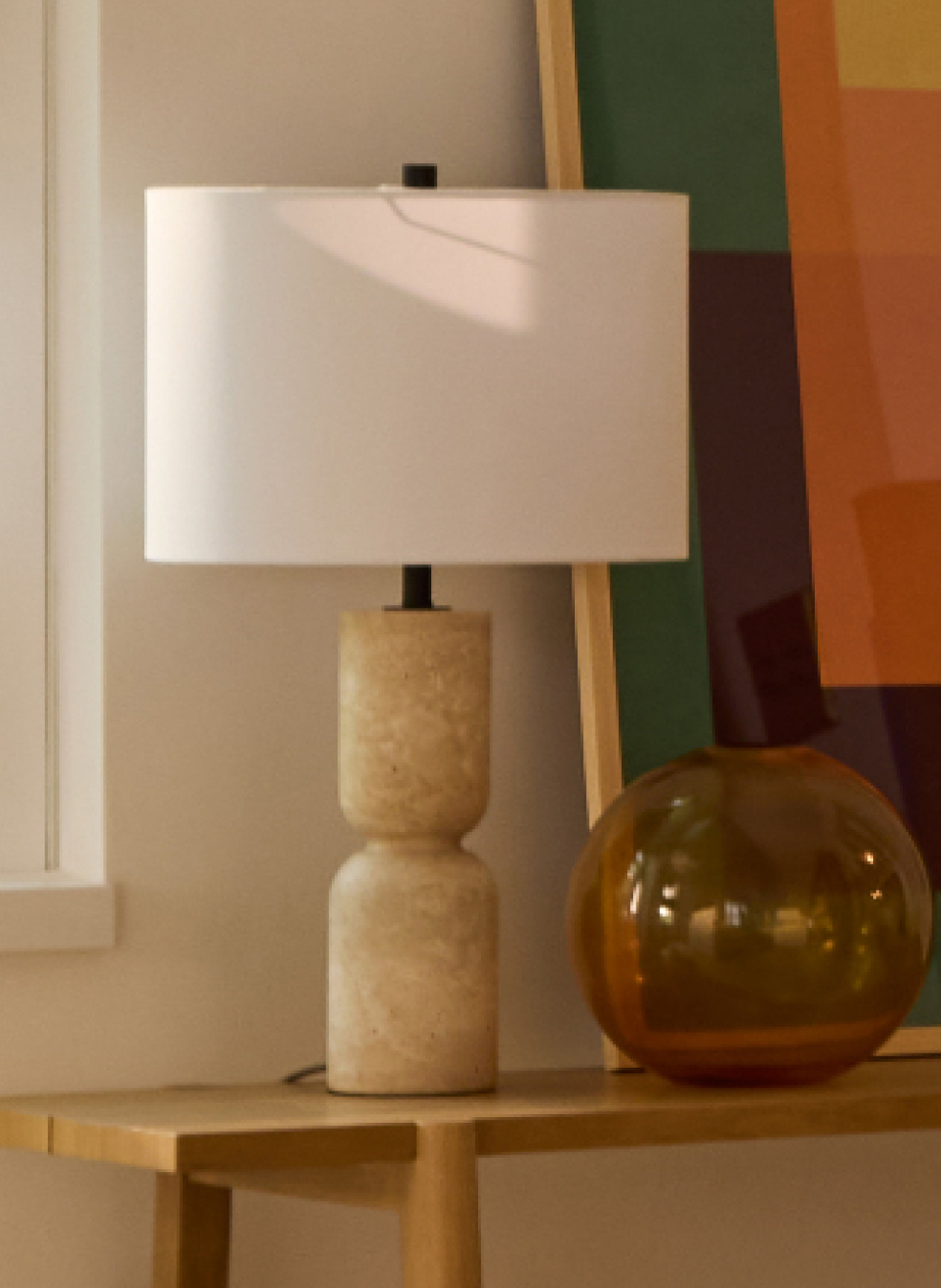 Table lamp with a travertine base and white shade.