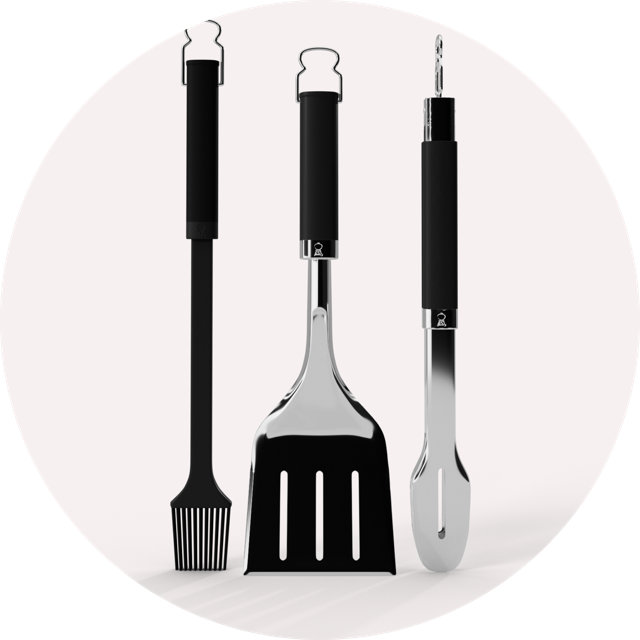 Set of three stainless steel grilling tools featuring black ergonomic handles, including a basting brush, spatula, and tongs.