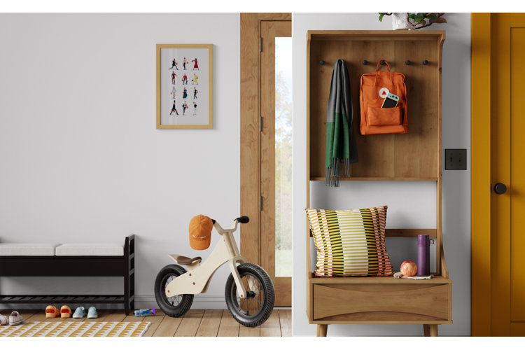 small entryway with a black bench with white cushions, wood hall tree, textured throw pillow, and striped area rug