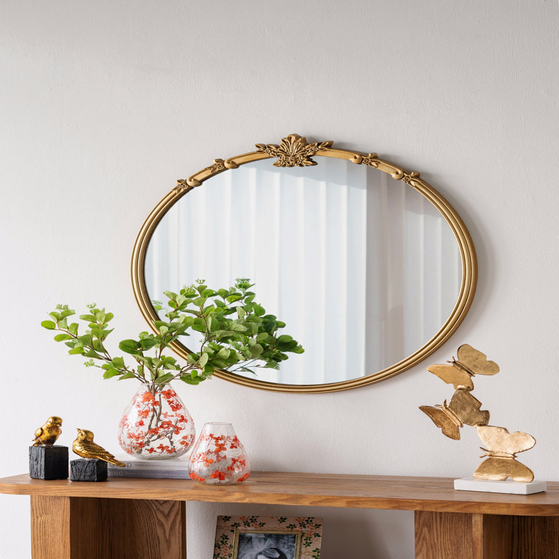 Miroir mural rond avec finition dorée et écusson décoratif