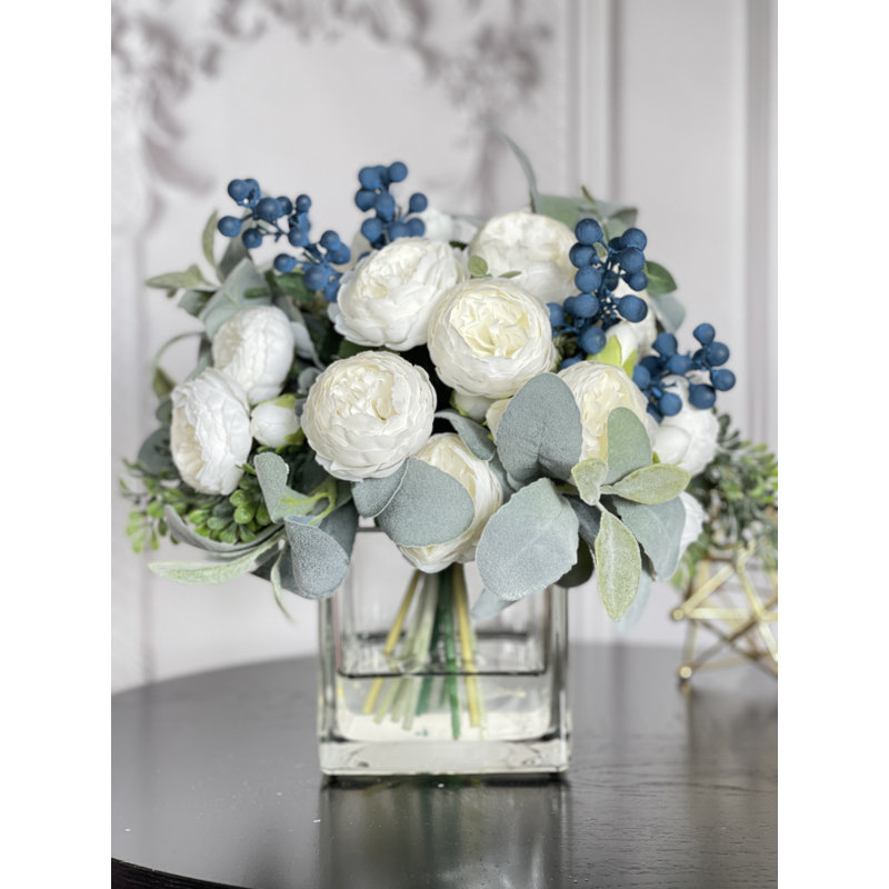 Grande pivoine blanche, baies bleues et arrangement de verdure