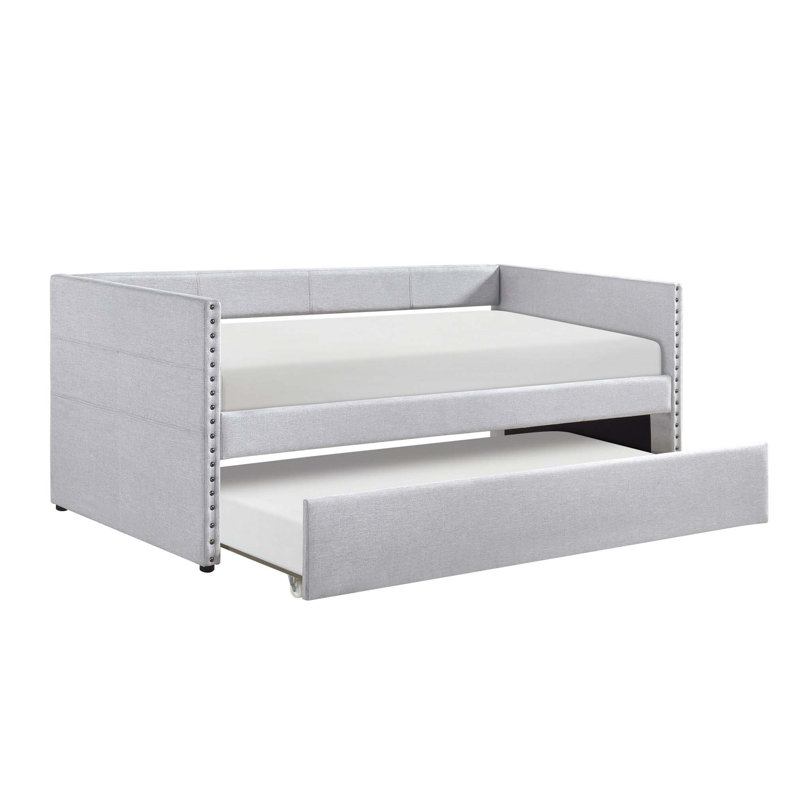 Lit de jour moderne avec couchette coulissante, poches de rangement latérales et garniture cloutée pour un espace d'invité polyvalent.
