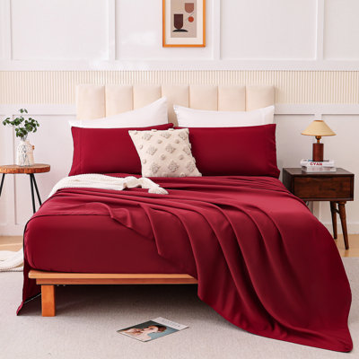 Lit quatre pièces rouge vin avec tissu en mélange de coton, confort en forme de nuage pour un sommeil nu, bord renforcé à l'effilochage, couleurs à faible saturation, différents types de lit double, combinaison d'impression en rouge, peau