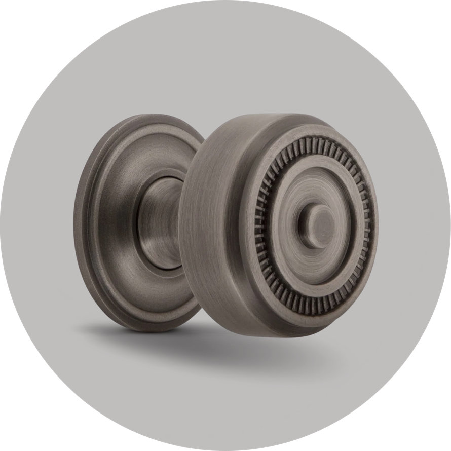 Round antique pewter door knob with a decorative fluted edge and matching circular rosette on a light gray background.