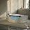 Baignoire tourbillon de coin pour 2 personnes 59 po DAHEAT, baignoire triangulaire de forme triangulaire avec 6 jets d'hydromassage, lumières DEL de chromothérapie et système de réglage pneumatique, conception en verre bleu latéral, drain central, certifié UL, certifié UPC, blanc laiteux
