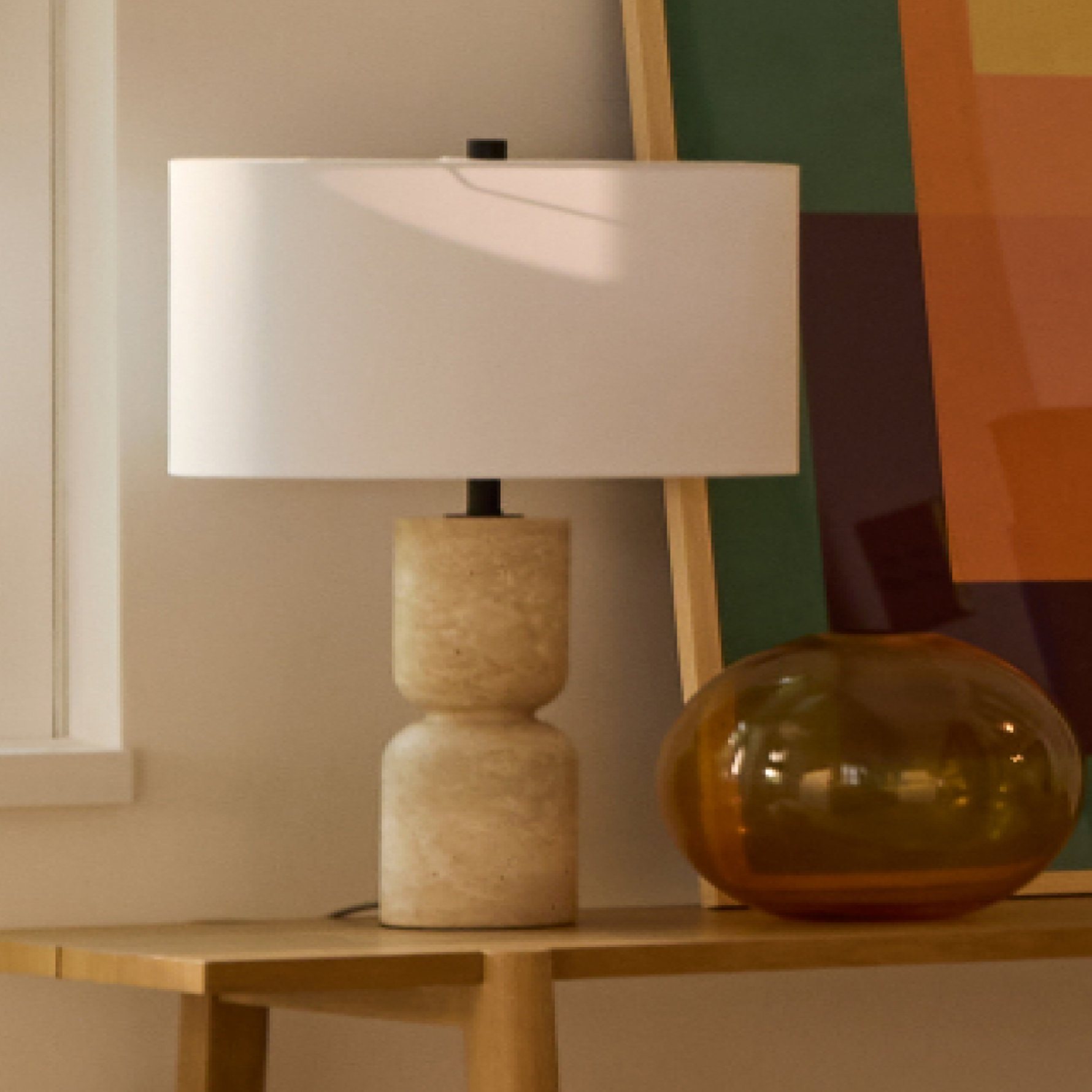 Table lamp with a travertine base and white shade.