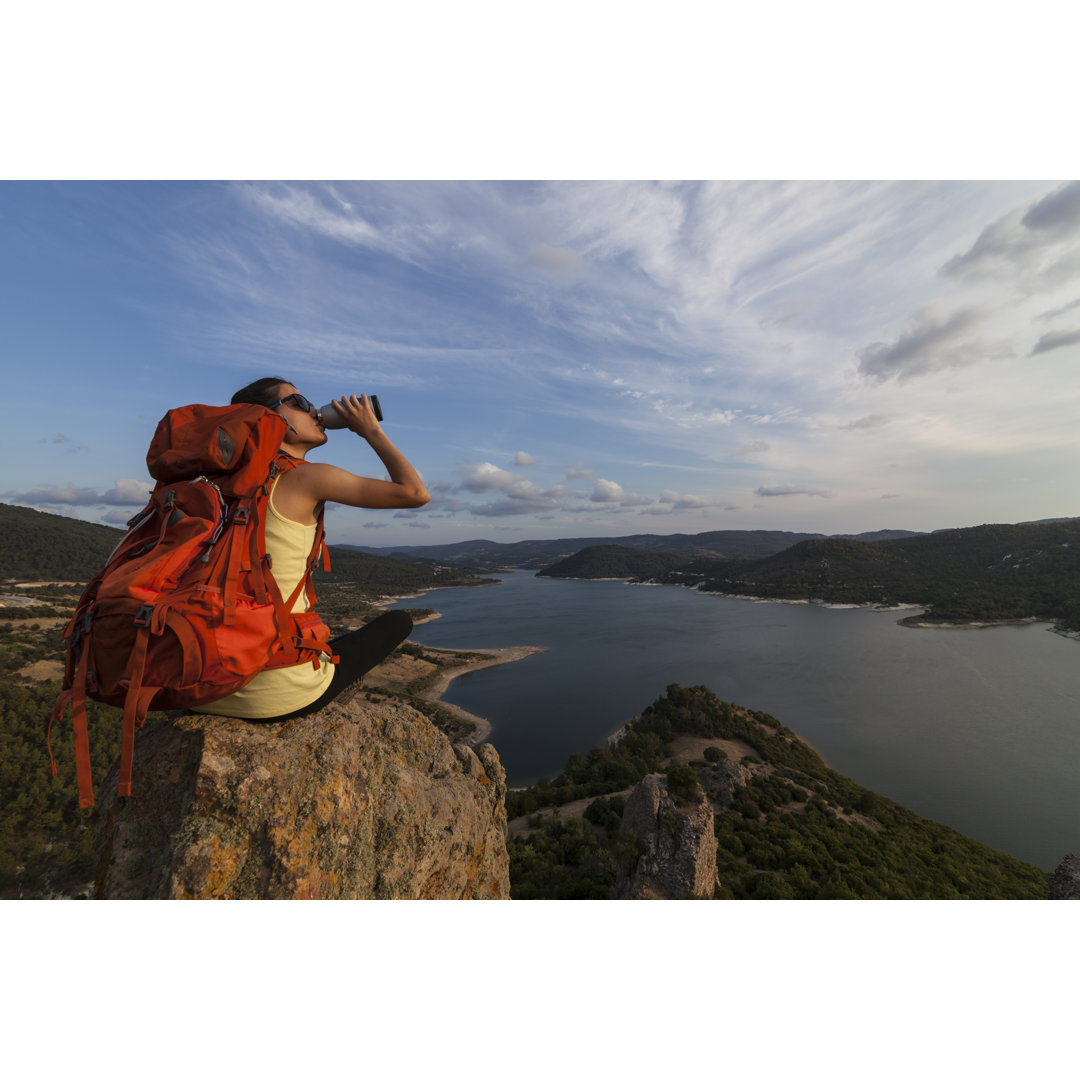 Wanderin trinkt Wasser auf der Spitze eines Felsens