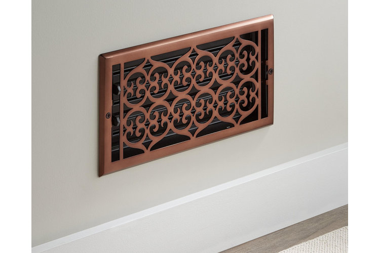Copper air vent on a wall above the baseboard