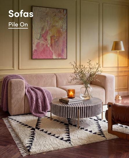 Sofas Pile On in a stylishly decorated living room featuring a blush sofa, a striped coffee table, and a plush patterned rug.