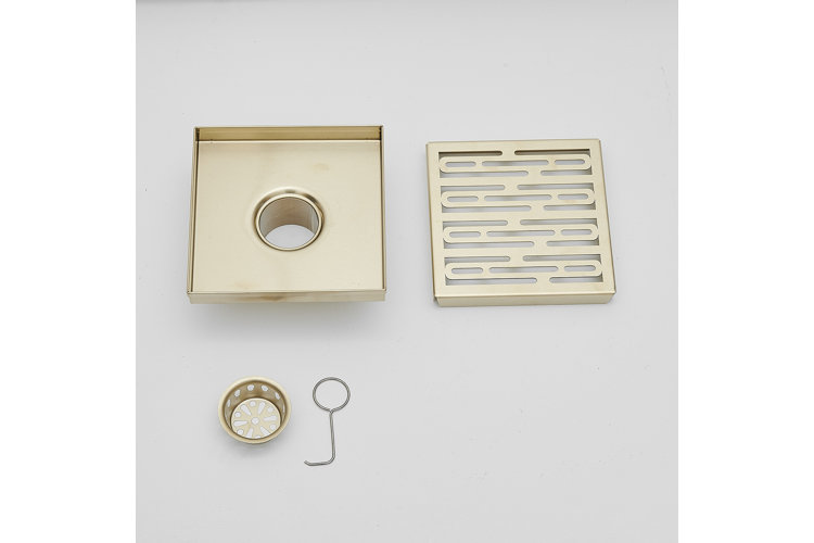 a square gold drain body beside a square gold drain cover, a round gold hair strainer, and a drain lift hook.