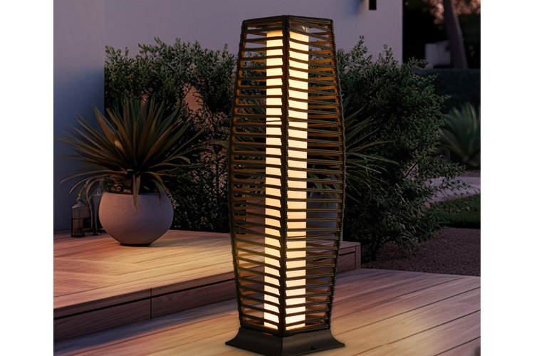 A column-shaped solar-powered floor lamp with a woven wicker frame positioned on a front porch step.
