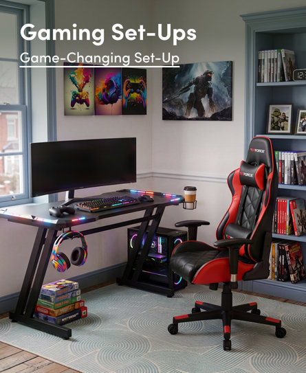 Gaming Set-Ups: Game-Changing Set-Up featuring a modern gaming desk with RGB lighting, a red and black racing-style gaming chair, and a PC setup in a room decorated with gaming wall art and shelves.