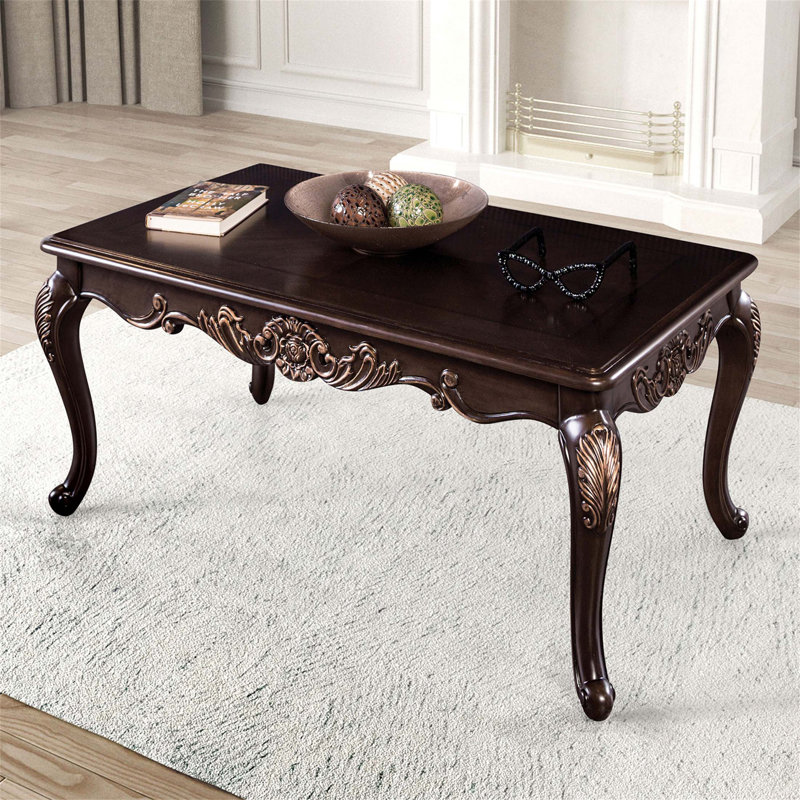Table basse de style traditionnel avec pieds courbés, structure en bois massif et motif sculpté orné au fini cerisier foncé