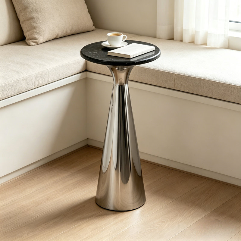 Table d'appoint haute sur pied, plateau d'aspect marbre noir et piètement conique en métal chromé poli, table basse moderne et mince pour salon et chambre.