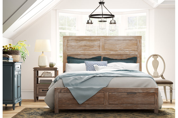 coastal farmhouse bedroom with a distressed wood bed, wagon wheel chandelier, and blue bedding