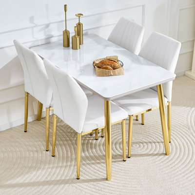 Ensemble de table de salle à manger moderne avec pieds coniques en métal dorés, comptoir double couche, texture imitation marbre et chaises ergonomiques à dossier en coquille.