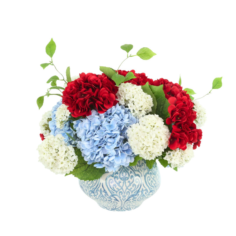 Arrangement d'hortensias rouges, blancs et bleus dans un vase en céramique