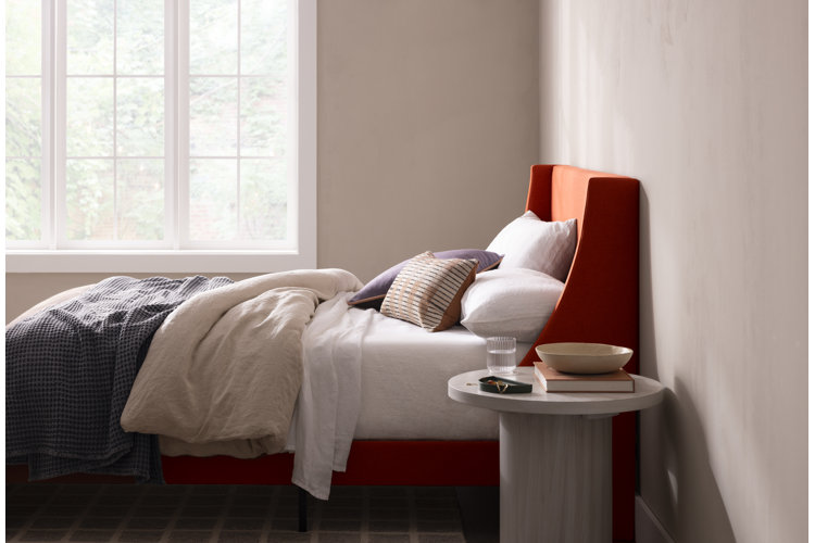 orange upholstered bed with white linen sheets, beige duvet cover, and a gray waffle-knit blanket