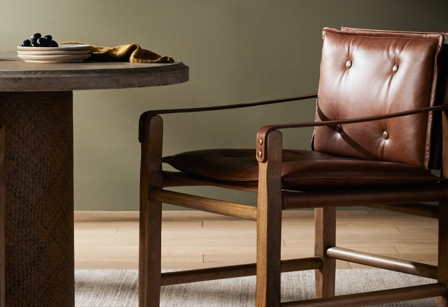 Close-up of a round wood table and a brown leather chair.