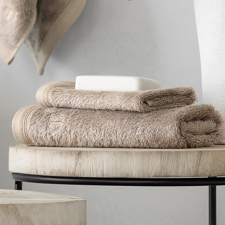 Tan-colored towels stacked on a wooden table with a bar of soap.