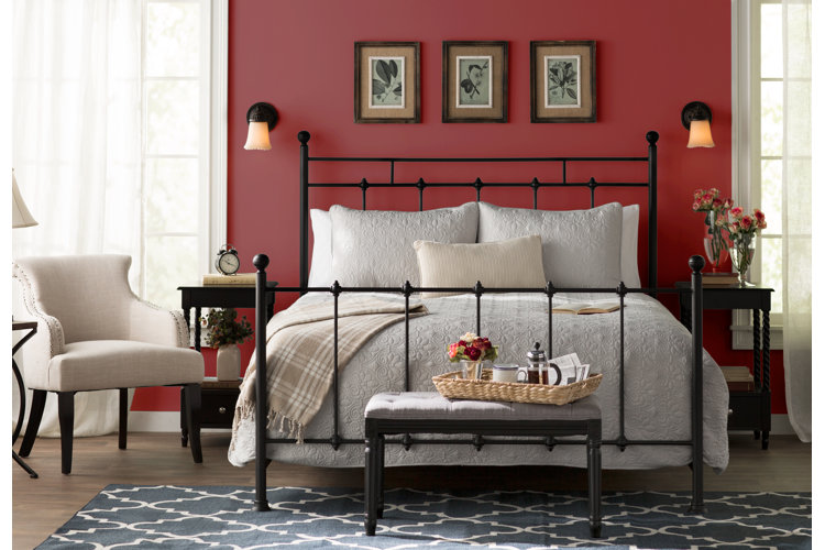 traditional-style bedroom with cherry red walls and an open-frame metal bed with white bedding