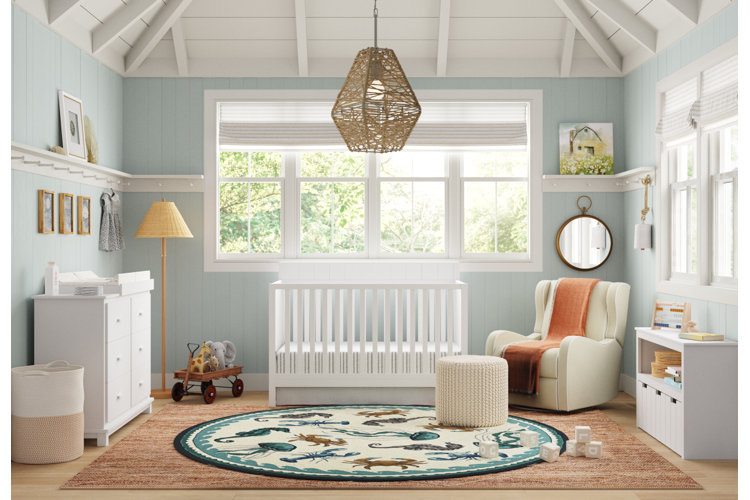 A blue and white nursery with blue paneled walls and a round area rug with sea creatures