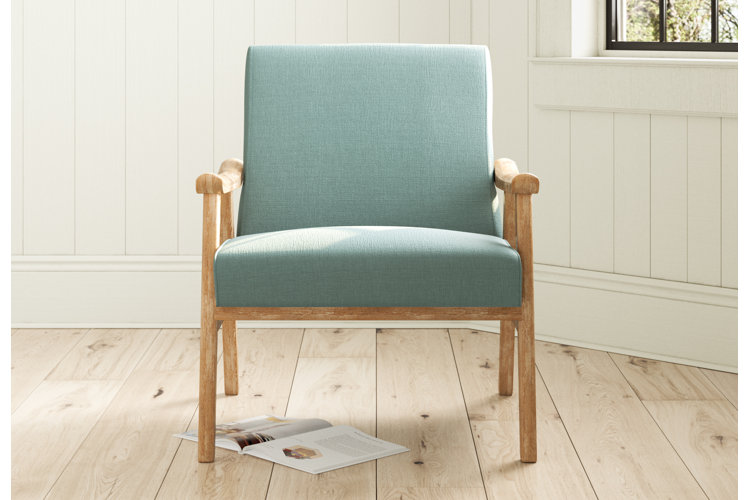 teal mid-century modern armchair on top of light-toned wood flooring