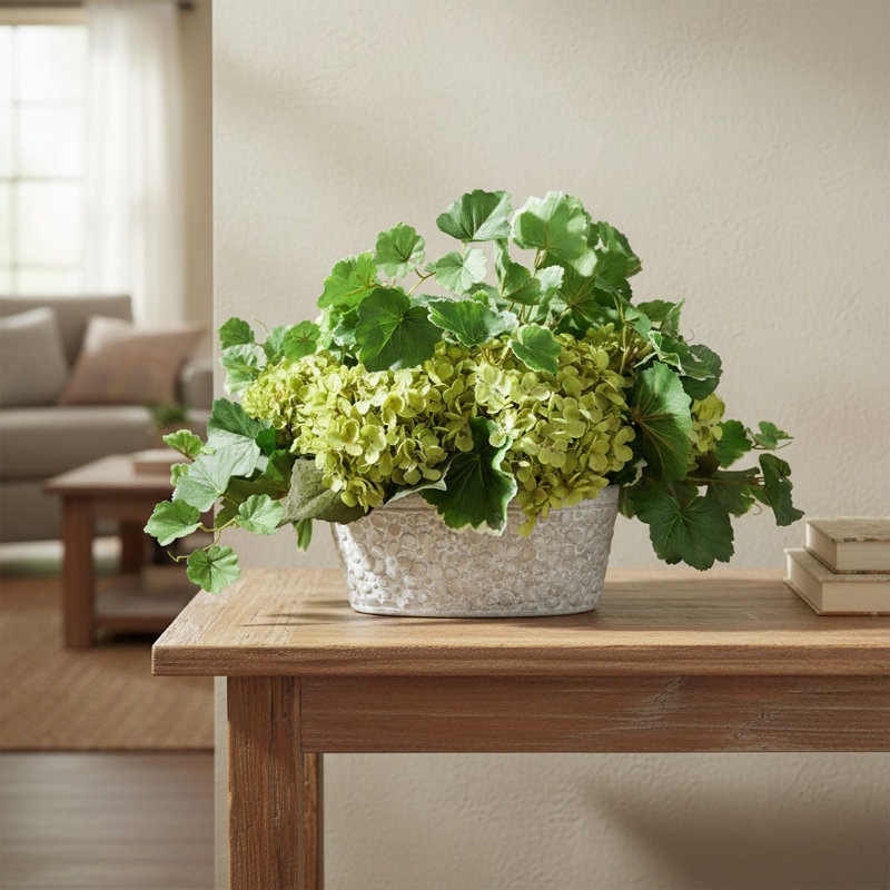 Hortensias disposés avec des feuilles de géranium dans un vase en pierre, Vert