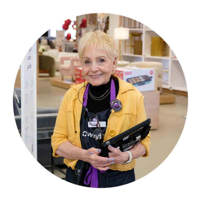 Smiling Wayfair employee in a retail store holding a tablet.