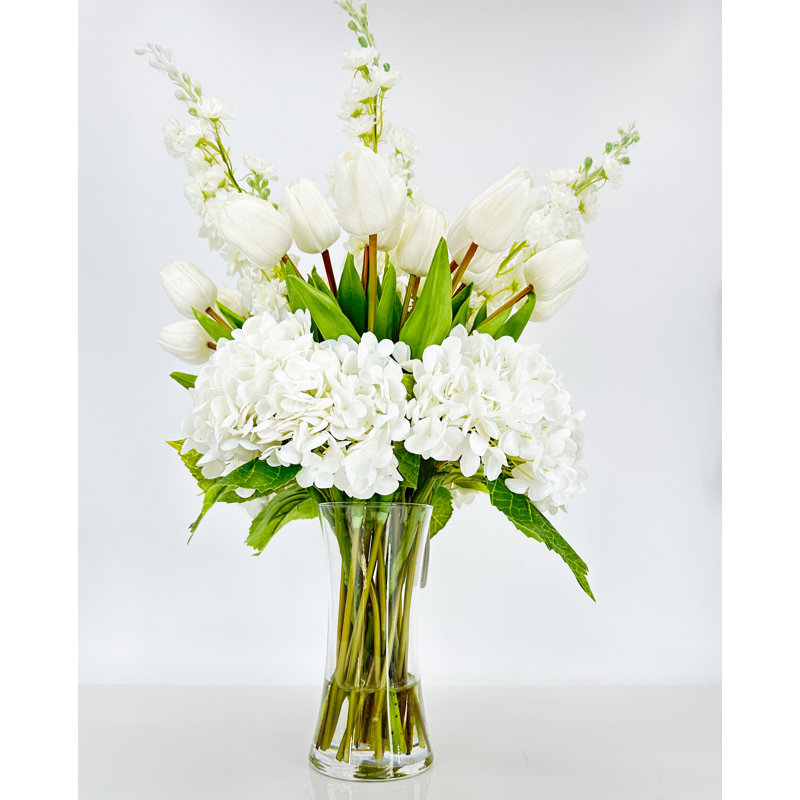 Pièce maîtresse artificielle, hydrangées et delphiniums dans un vase en verre