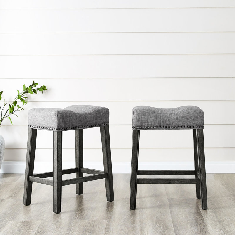 24" Gray Upholstered Backless Saddle Seat Counter Stools   Of 2 . Crafted From Real Wood With Weathered Appearance. Grey Upholstery. Contemporary Design. 18"W X 13"D 25"H. For Residential Use.