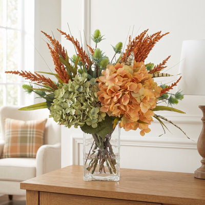 Arrangement d'hortensias et de bruyères dans un vase en verre