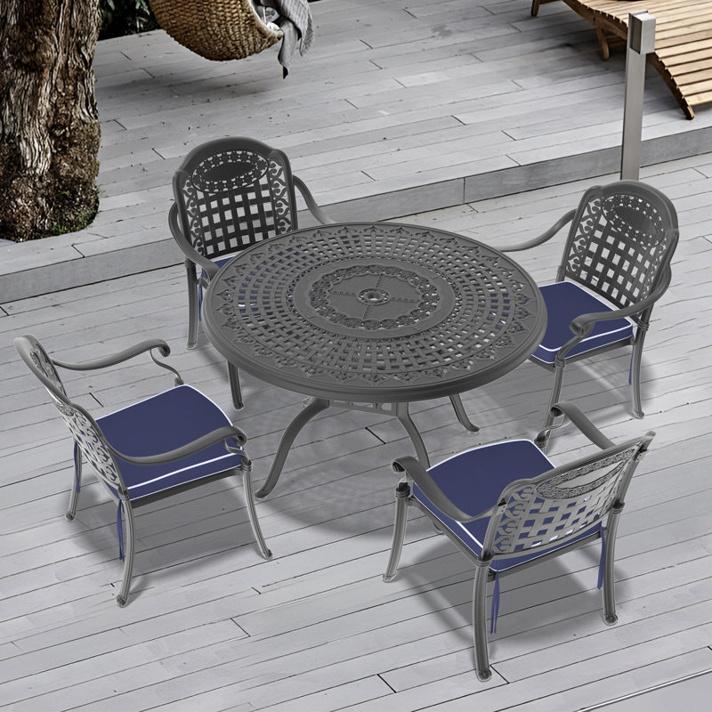 Ensemble de salle à manger d'extérieur rond en aluminium moulé de 5 pièces (120 cm) avec trou pour parasol, 4 chaises empilables et coussins bleus.