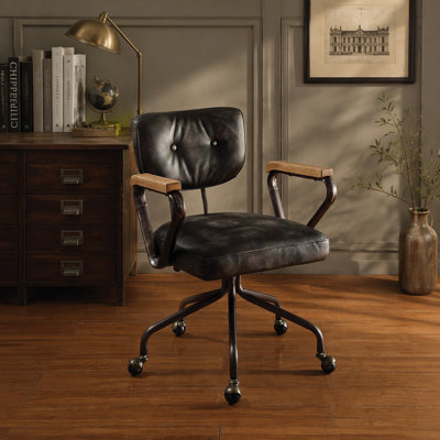 Fauteuil de bureau pivotant vintage en similicuir, orné de clous décoratifs, avec accoudoirs en bois et piètement en métal, sans relevage.