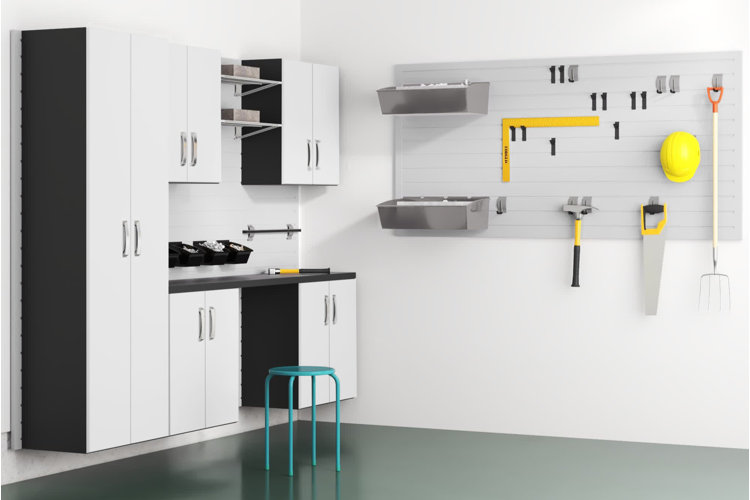 clean garage with white storage cabinets and a slatwall panel