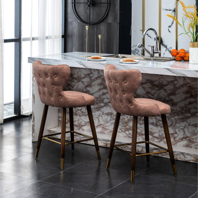 Tabourets de bar roses de style moderne du milieu du siècle (lot de 2) - Revêtement en similicuir avec garniture cloutée, aspect daim, dossier incurvé, pieds fuselés en noyer, repose-pieds en métal doré.