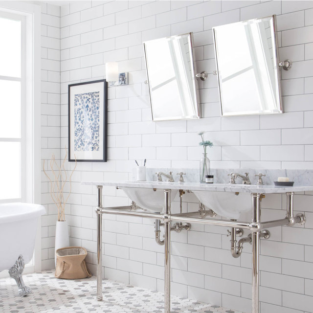 Bathroom with double vanity sink, white subway tile, and clawfoot tub.
