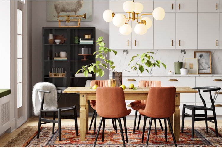 modern eat-in kitchen with wooden dining table, upholstered dining chairs, white cabinetry, and gold sculptural chandelier