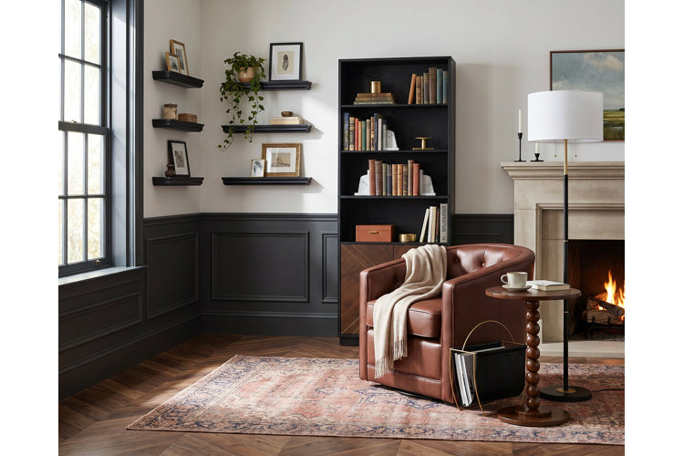 reading corner in a traditional living room featuring a fireplace, leather barrel chair, Oriental area rug, freestanding wooden bookcase, and six floating wall shelves with artwork and decor