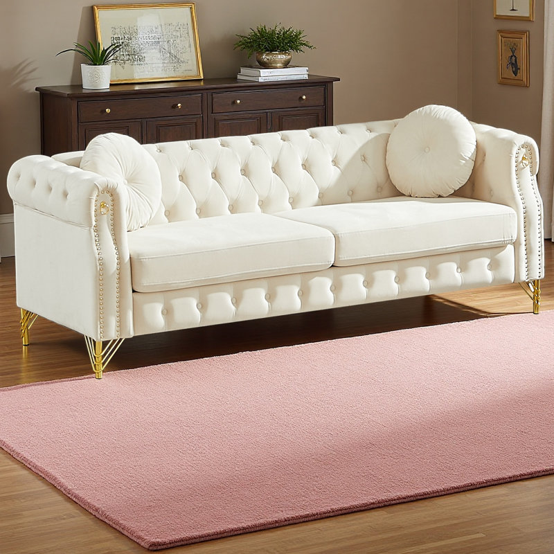 Canapé Chesterfield de 82 pouces en velours avec deux coussins ronds, avec des détails cloutés en cuivre et des boutons capitonnés, avec des pieds en métal. La conception en boucle permet de suspendre des ornements de dessins animés.