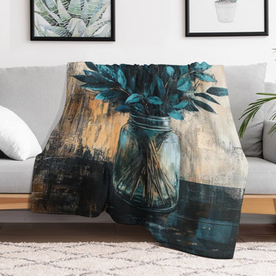 Feuilles bleu sarcelle dans un bocal en verre sur une jeté en flanelle de luxe en bois foncé, couverture douce et chaude pour le canapé-lit du salon
