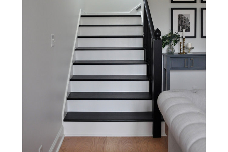 A set of stairs with white risers, black stair treads, and black railings.