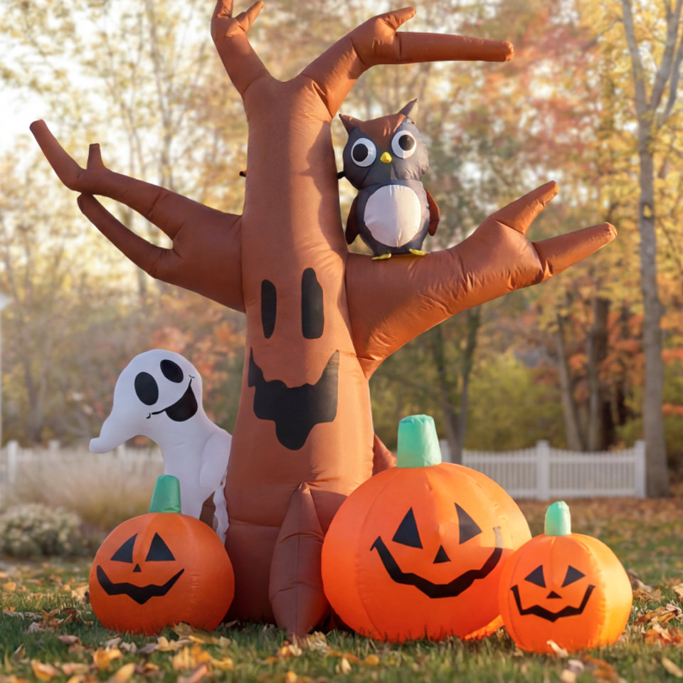 Inflatable Halloween decoration featuring a spooky tree, an owl perched on a branch, a friendly ghost, and three smiling jack-o'-lanterns on a grassy lawn.