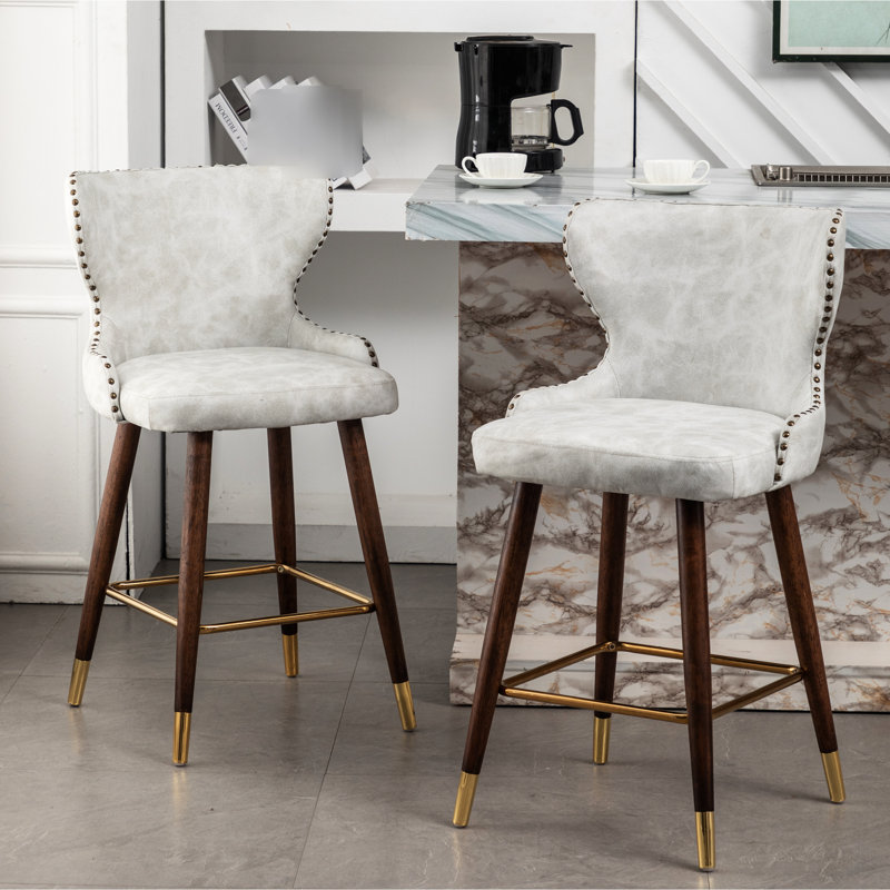 2 tabourets de comptoir modernes de style Mid-Century, siège en similicuir, dossier capitonné, repose-pieds incurvé doré, siège avec garniture cloutée, pieds en bois massif