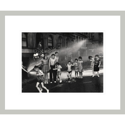 [Enfants jouant dans de l'eau pulvérisée à partir d'une bouche d'incendie à ciel ouvert de l'Upper West Side à New York] par Weegee - Impression giclée encadrée